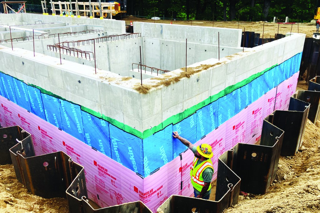 Construction of tertiary treatment system from the side showing a team member inspecting the foundation