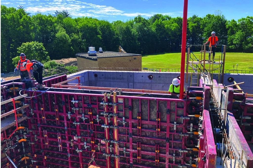 Construction of sludge holding tanks from the top of the area showing workers and wall bracing